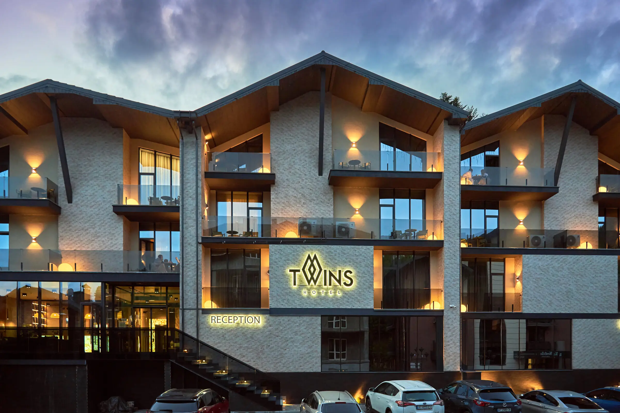 Фасад готелю Twins Hotel & Spa у Буковелі ввечері з підсвіткою, фото Fomich Hotels